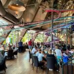 A bustling indoor dining area with colorful roller coaster tracks overhead