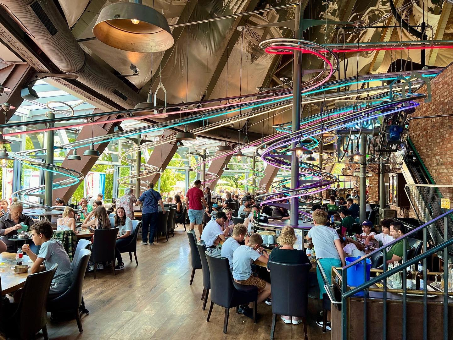 Food Loop A bustling indoor dining area with colorful roller coaster tracks overhead