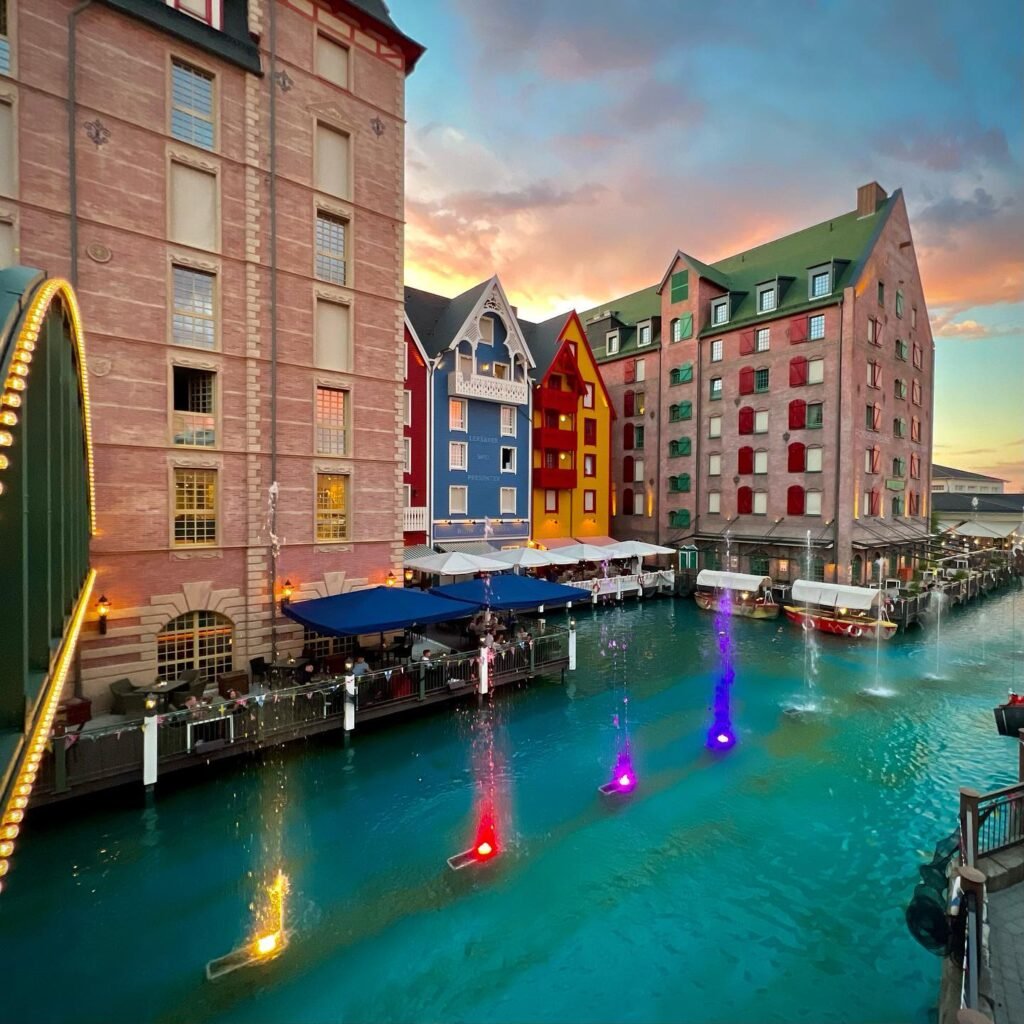 Bunte Gebäude am Hafen bei Sonnenuntergang, beleuchtete Brunnen im Wasser, historisches Stadtbild