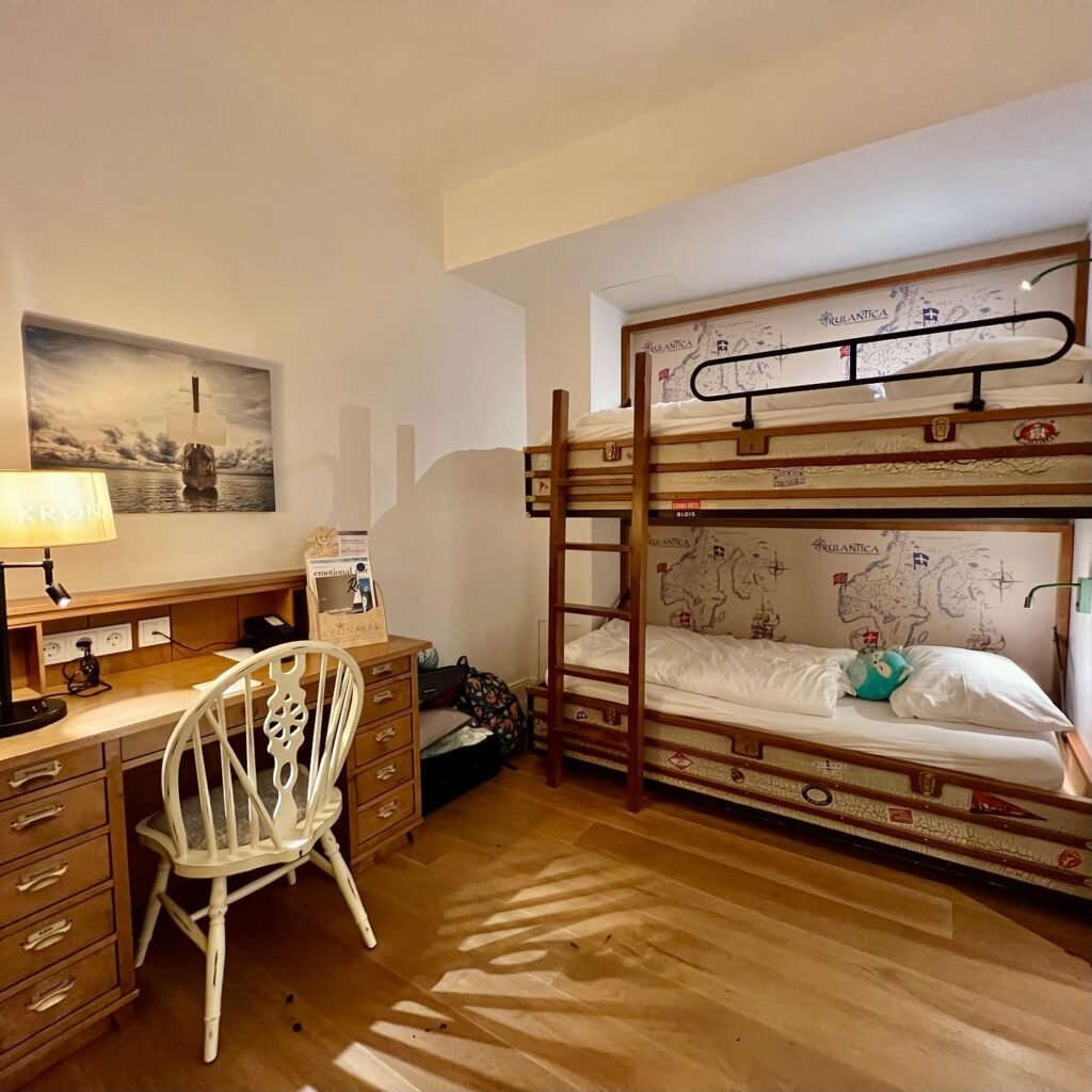 A warm and inviting guest room featuring rustic wooden bunk beds and a vintage-style desk with a white chair.