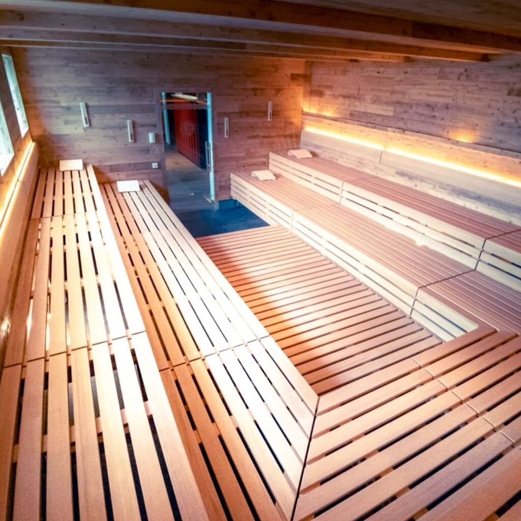 Spacious wooden sauna room with warm lighting and multiple seating sections