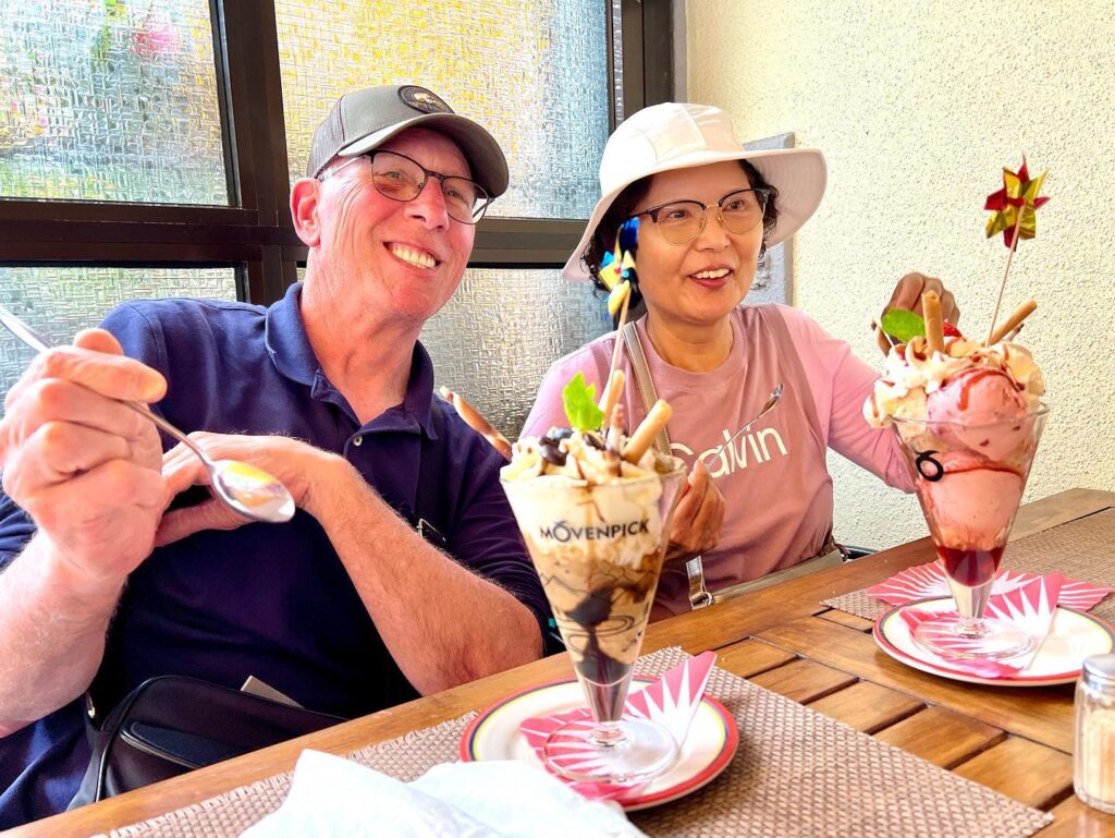 Two people enjoying elaborate bubble waffles at a table, with detailed close-ups of desserts and spoons.
