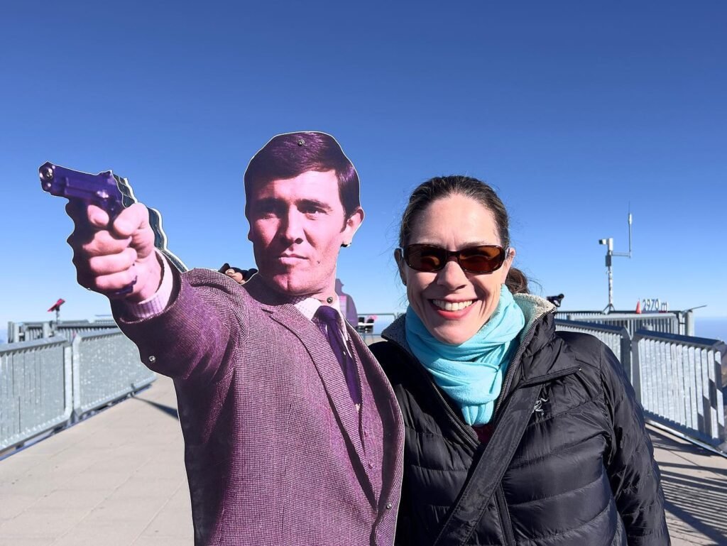 A couple poses with a toy gun in a playful manner on the Seattle Monorail. Blue sky and cityscape visible in the background.