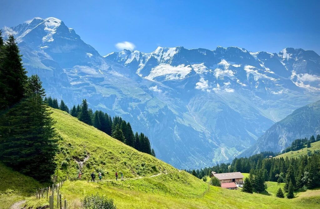 A collage of alpine scenery featuring snow-capped mountains, lush green meadows, and alpine cabins.