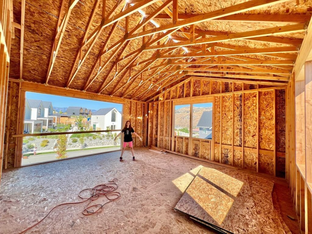 Interior view of a house under construction showing exposed wood framing and flooring samples.