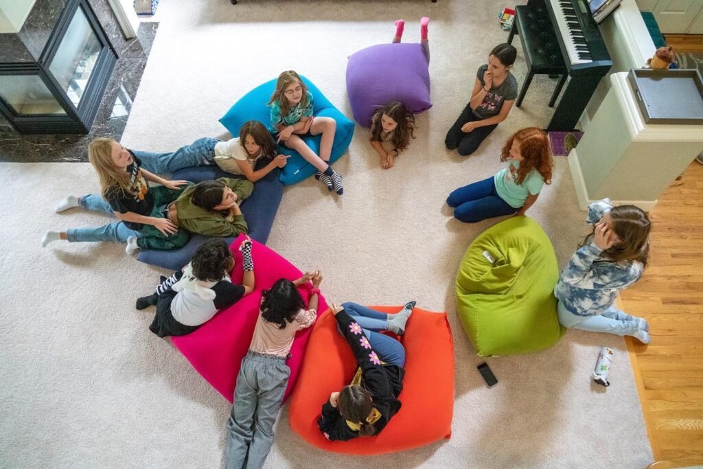 Overhead view of a diverse group of young people relaxing on colorful beanbags in a living room, sharing a moment of connection.