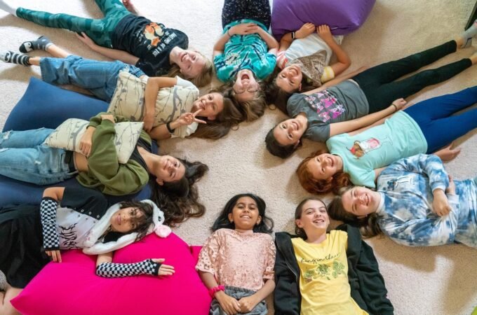 A group of people lying on the floor arranged in a circular pattern forming a star shape.