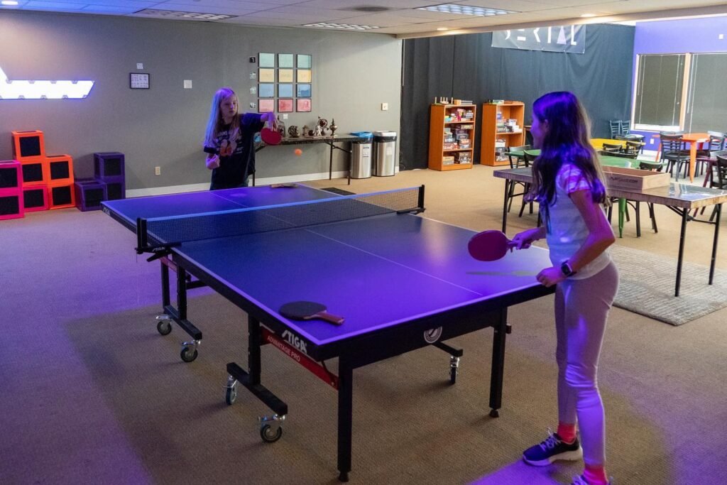 Youth playing ping pong in a recreation center.