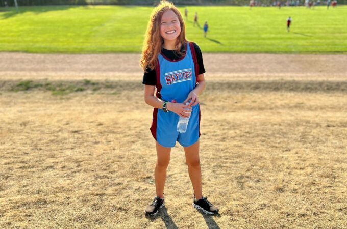A smiling soccer player wearing a blue and red outfit stands on a field at a local sports event. This image captures moments from our life adventures in the Pacific Northwest.