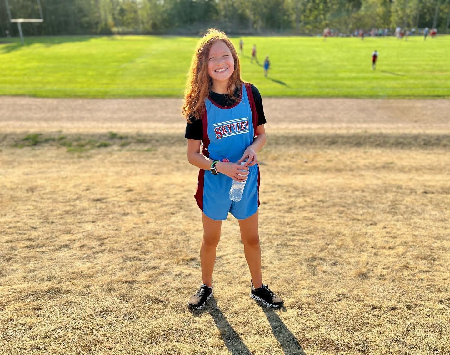 A smiling soccer player wearing a blue and red outfit stands on a field at a local sports event. This image captures moments from our life adventures in the Pacific Northwest.