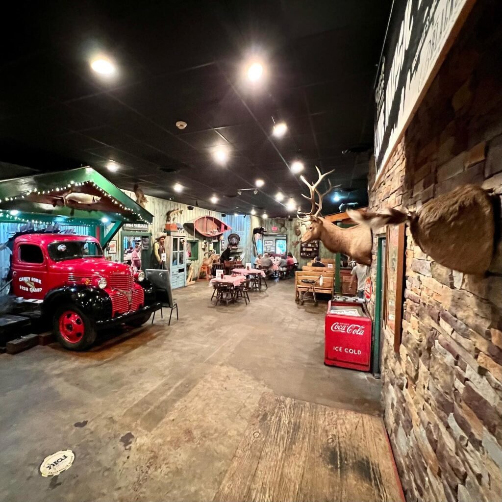 A vibrant indoor dining space featuring a vintage red truck, brick walls, and mounted antlers.