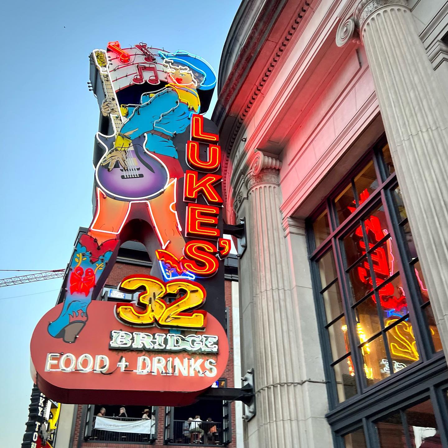 Vibrant neon sign for Luke's 32 adorning the exterior of the historic Paragon Building in Seattle. A colorful electric guitar icon highlights the restaurant's musical performance theme.
