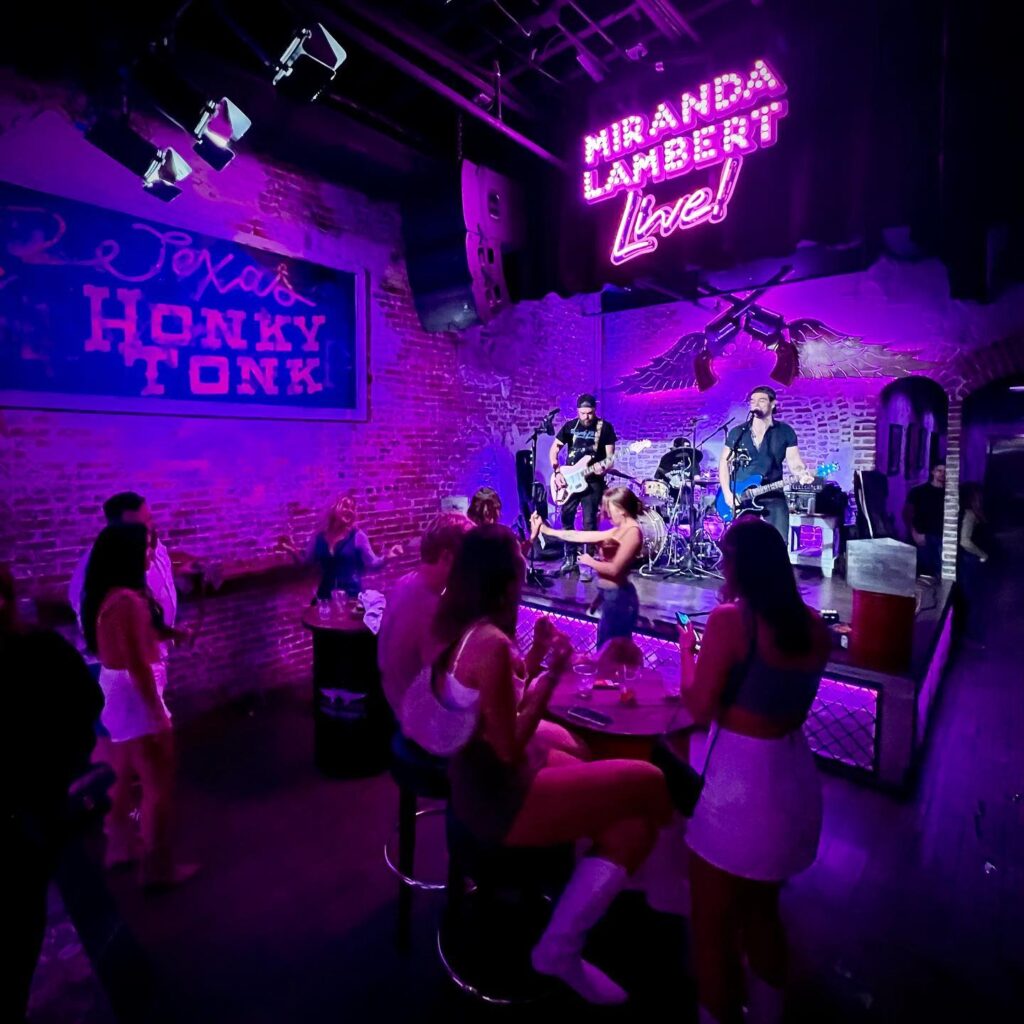 A lively scene inside El Toros Honky Tonk featuring a live band, vibrant purple lighting, and patrons enjoying the atmosphere.