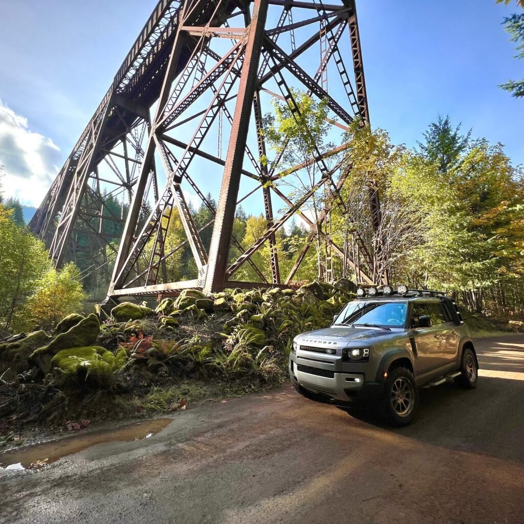 A truck parked next to the historic Milner Dam Trestle, surrounded by lush greenery.