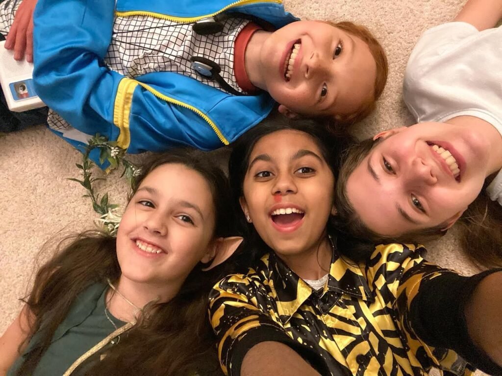A family taking a playful selfie on the floor in colorful costumes.