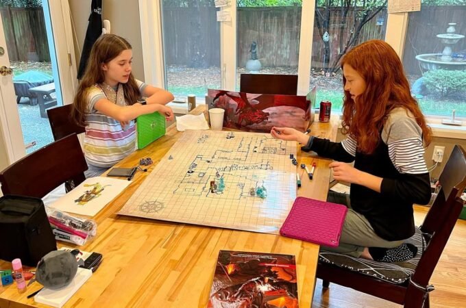 A fun family game night playing Settlers of Catan with a beautiful view of the backyard and a fountain outside the glass doors.