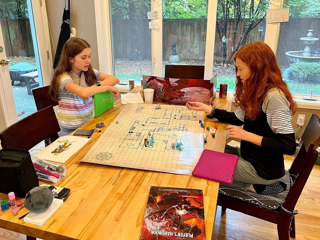 D&D A fun family game night playing Settlers of Catan with a beautiful view of the backyard and a fountain outside the glass doors.