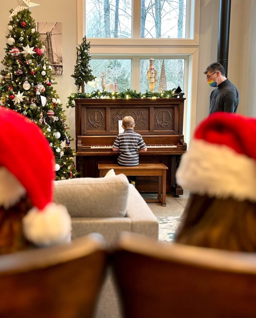A festive living room scene with Santa hats in the foreground and a child playing the piano in the background.
