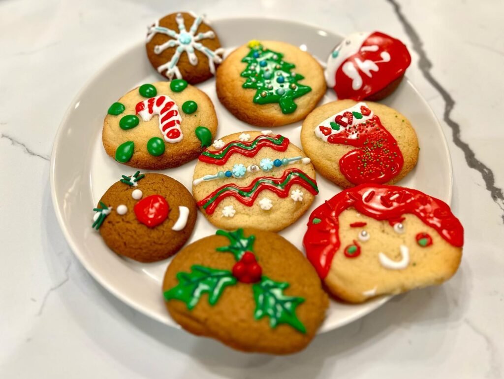 A plate of decorated gingerbread cookies featuring Santa, stockings, trees, and snowflakes.