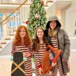 Fractured Foot Family members in matching red and white striped pajamas holding a skateboard and harp in front of a Christmas tree.