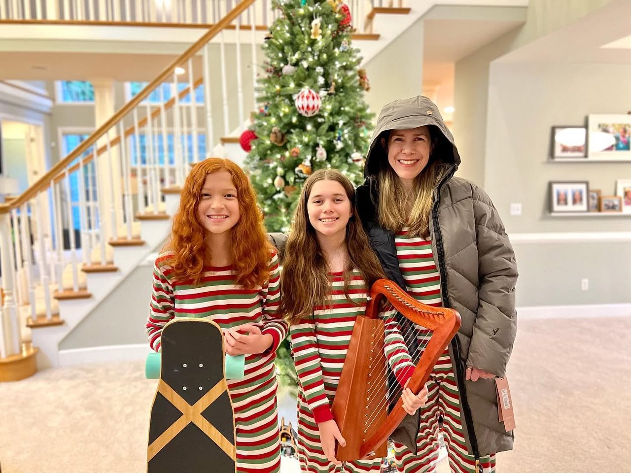 Merry Christmas Family members in matching red and white striped pajamas holding a skateboard and harp in front of a Christmas tree.
