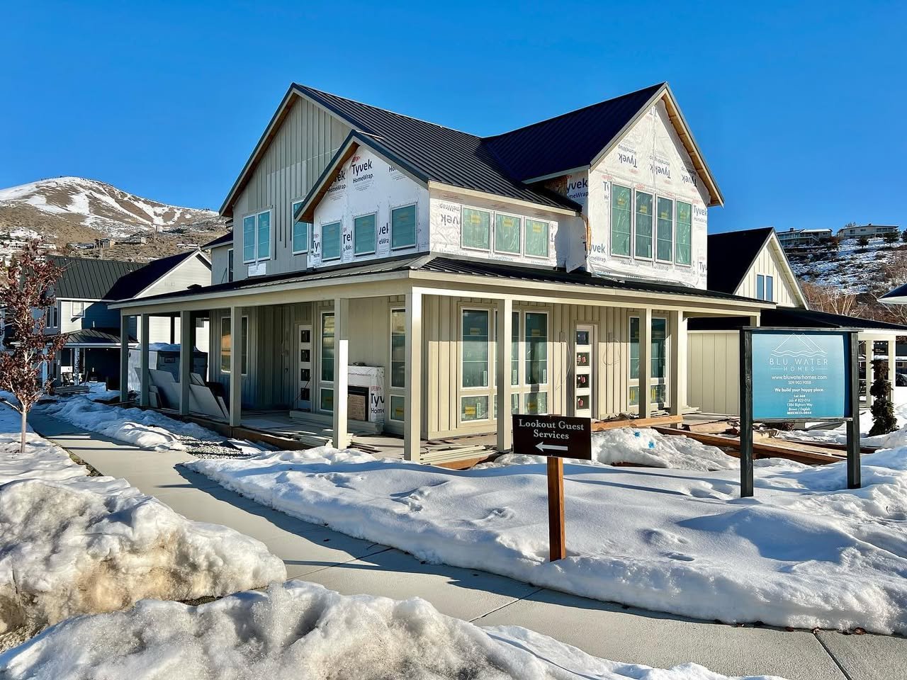 A charming mountain chalet with snow covering the ground and surrounding landscape under a clear blue sky.