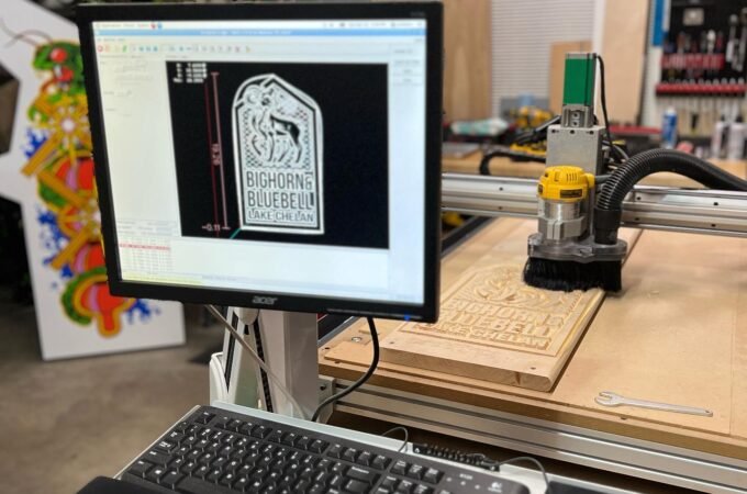 CNC router in a workshop with a computer displaying the design being cut.