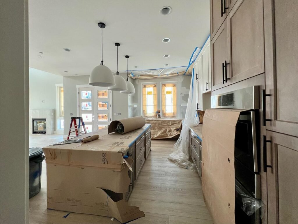 A kitchen under renovation with plywood cabinets and construction materials visible.