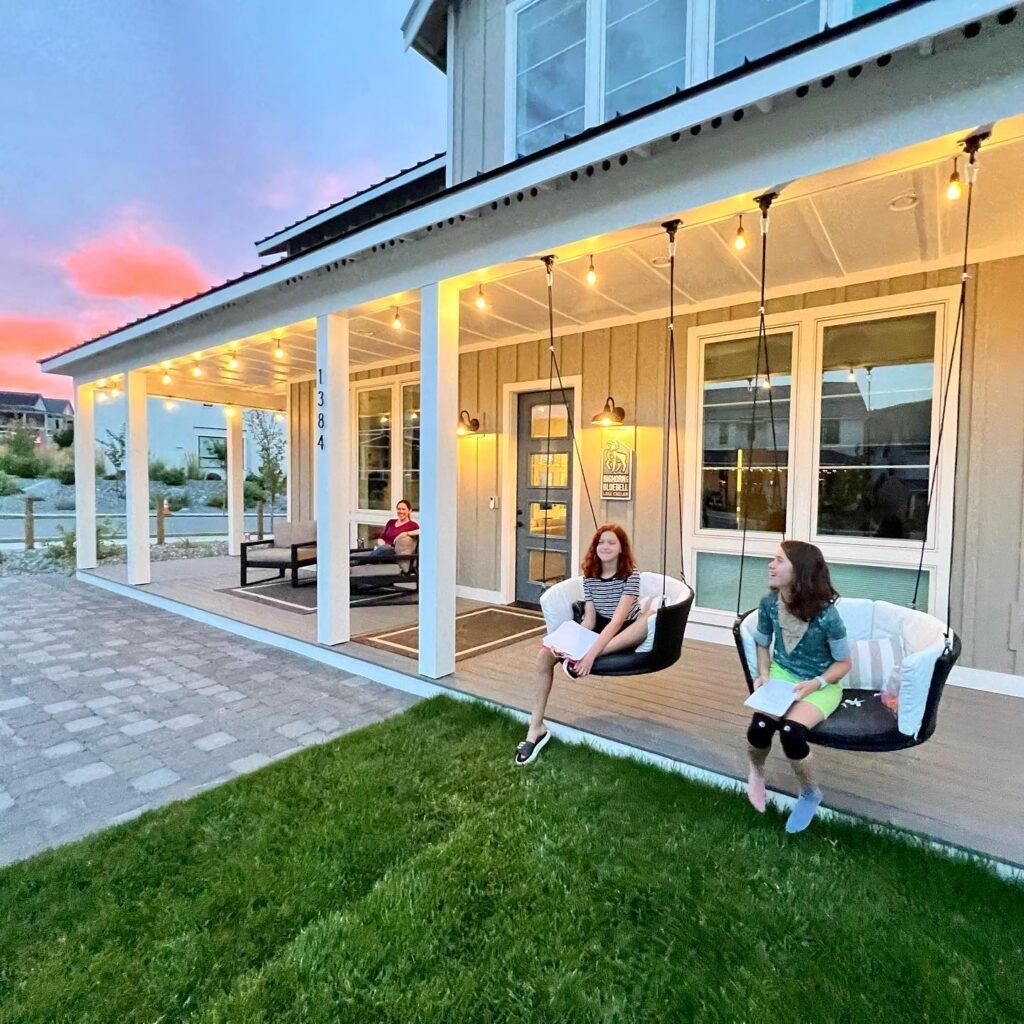 Two people relaxing on porch swings with a vibrant sunset in the background.