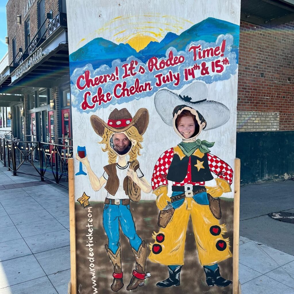 A colorful cardboard cutout advertising Lake Chelan Rodeo with date July 14th and 15th on a sidewalk.