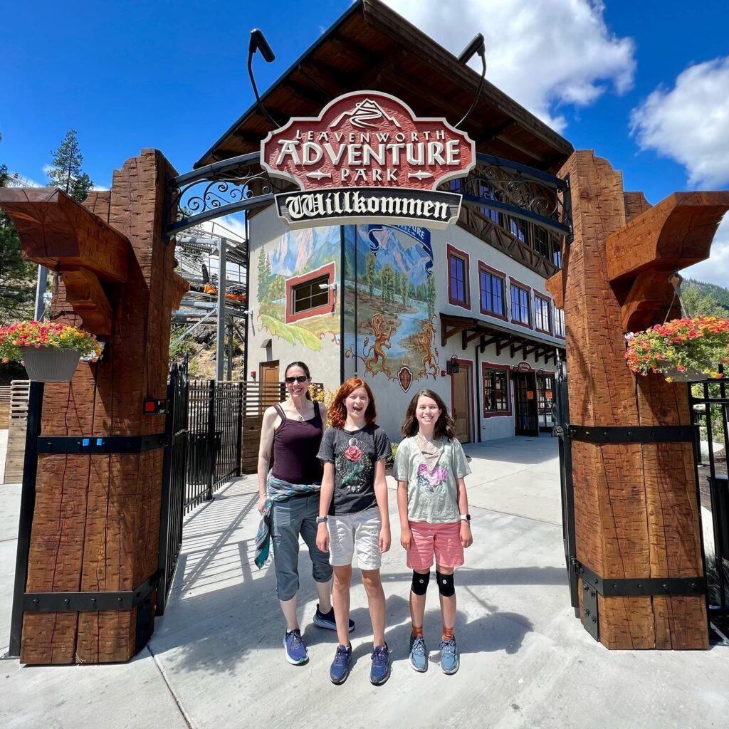 Family posing at the Adventure Park welcome sign in Breckenridge, Colorado.