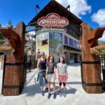 Family posing at the Adventure Park welcome sign in Breckenridge, Colorado.
