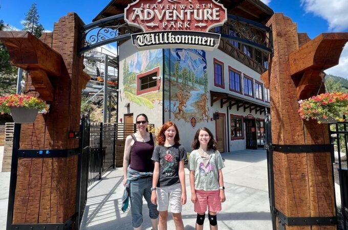Family posing at the Adventure Park welcome sign in Breckenridge, Colorado.
