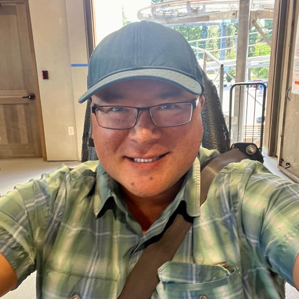 A person in a teal cap and green plaid shirt smiles on a moving walkway.