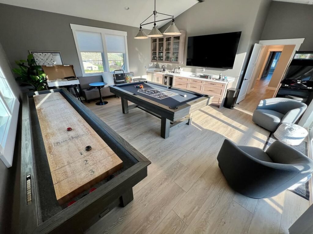 A spacious indoor game room featuring a shuffleboard table, a pool table, and modern seating.