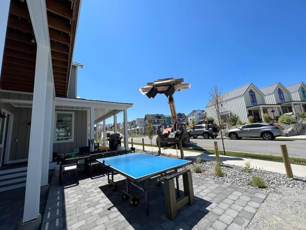 A nice outdoor setting with a ping pong table and modern houses under a clear, sunny sky.