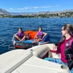 Summer at Lake Chelan Several people wearing life jackets are swimming and using a raft near a boat on a bright, sunny day in the Okanagan Valley.