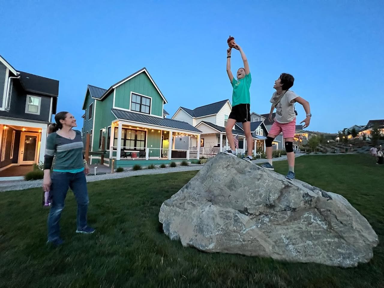 Summer at Lake Chelan A group of people enjoying a sunny day with a large rock in the grassy area in front of colorful houses.