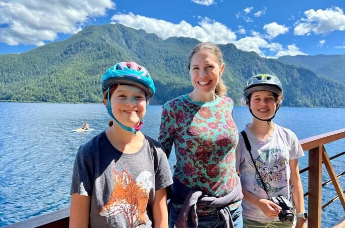 A group of people wearing helmets enjoy a boat ride on a lake with mountains in the background.