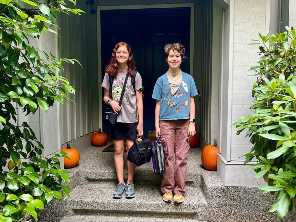 Two students stand on a porch with pumpkins, ready for the new school year.