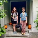 Two students stand on a porch with pumpkins, ready for the new school year.