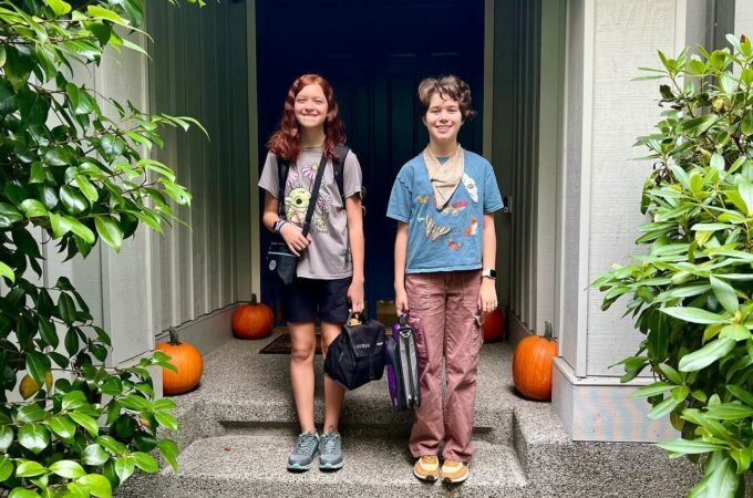 Two students stand on a porch with pumpkins, ready for the new school year.