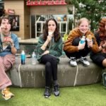 A family of four enjoys together ice cream cones on a stone bench outdoors, capturing a relaxed and happy moment during a trip in the Pacific Northwest.