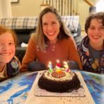 The Palazzo Resort Hotel & Casino A family smiles together for a birthday photo with a chocolate cake with lit candles on the table.
