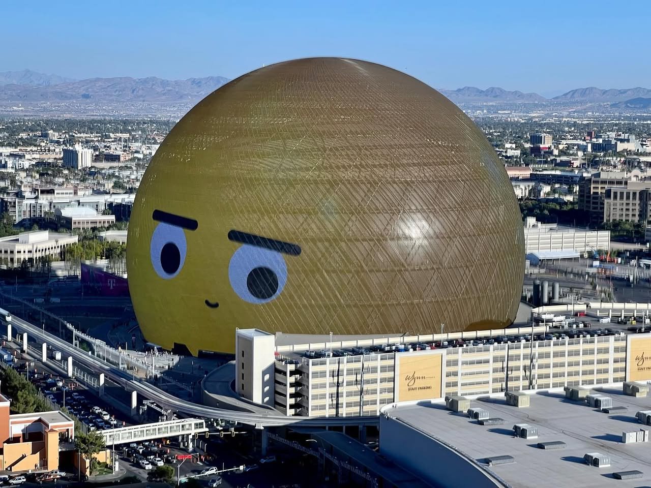 The Palazzo Resort Hotel & Casino An aerial view of the large spherical structure known as The Sphere in Las Vegas. The building features a golden exterior and a face printed on its surface.