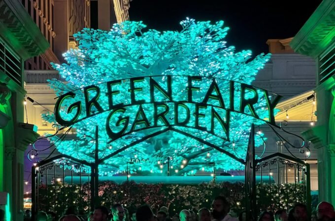 An illuminated tree and sign spelling out Green Fairy Garden at night.