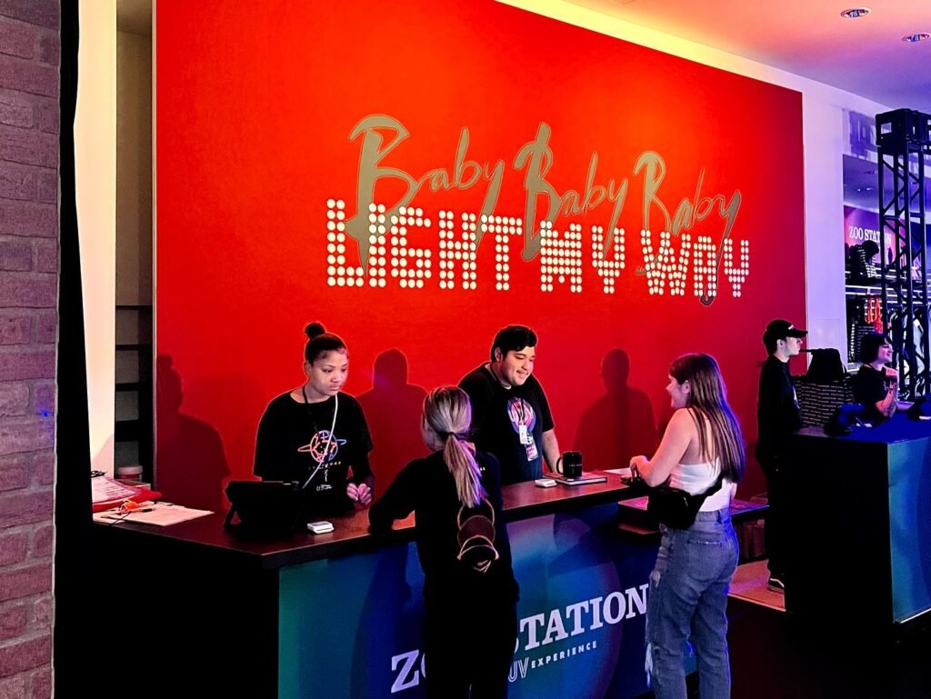 A bright red branded wall with LED text at a Zappos headquarters event