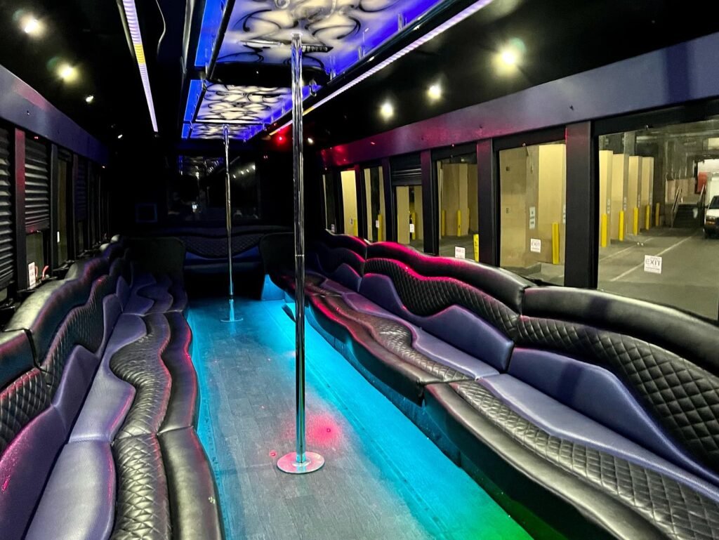 The interior of a party bus featuring colorful LED lighting, quilted black leather-lined seating, and a vibrant blue glowing aisle.