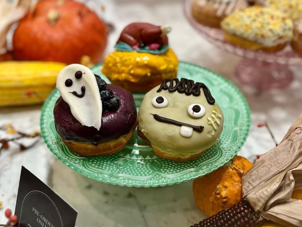 A delightful spread of Halloween cupcakes featuring spooky faces, set against a backdrop of pumpkins and autumn decor.