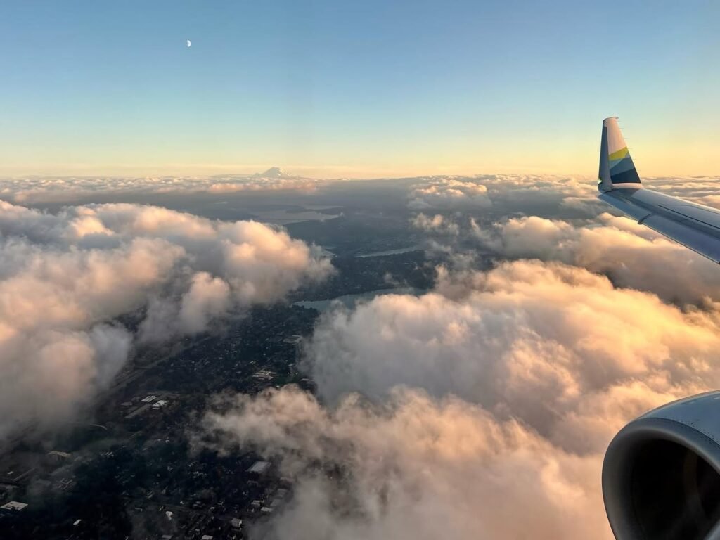 View from an airplane window overlooking a dense sea of clouds at sunset